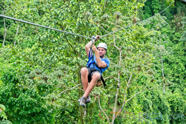 A Man Zip Lining Sitting Down Los Canones Canopy Tour La Fortuna
 - Costa Rica
